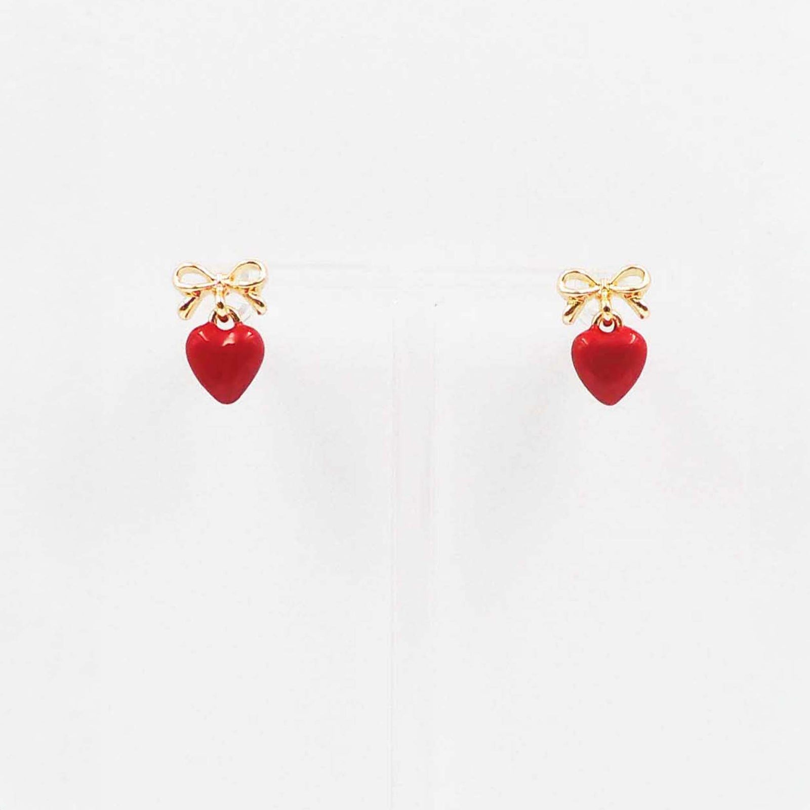 Gold bow stud earrings with dangling garnet red enamel heart charm.