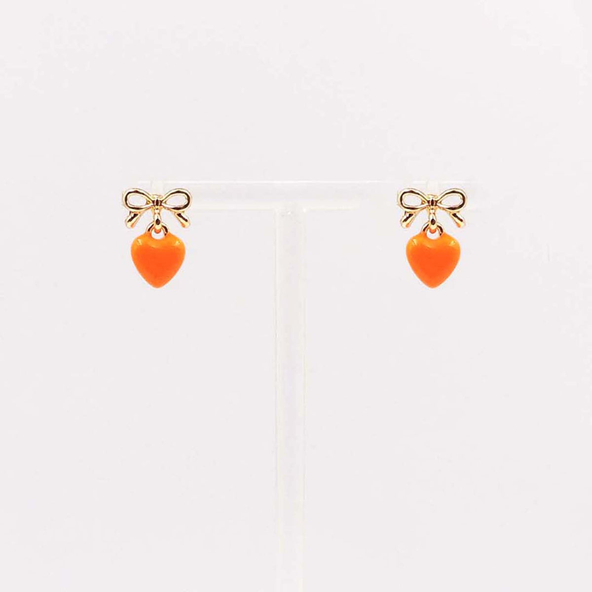 Gold bow stud earrings with dangling bright orange enamel heart charm.