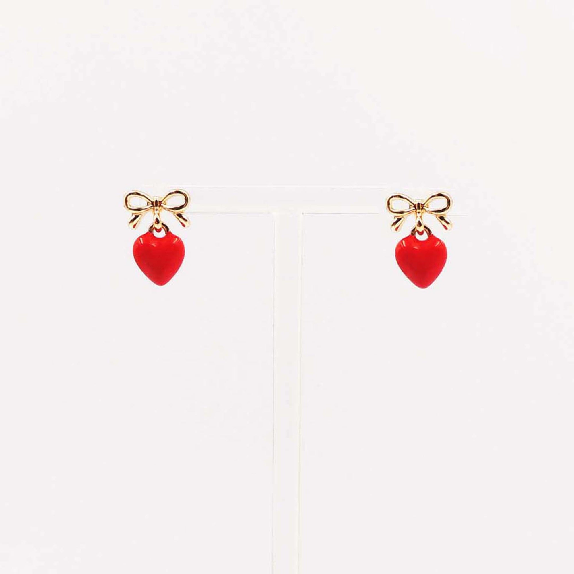 Gold bow stud earrings with dangling red enamel heart charm.