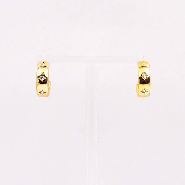 Gold huggie hoop earrings with starburst engravings and crystal accents.