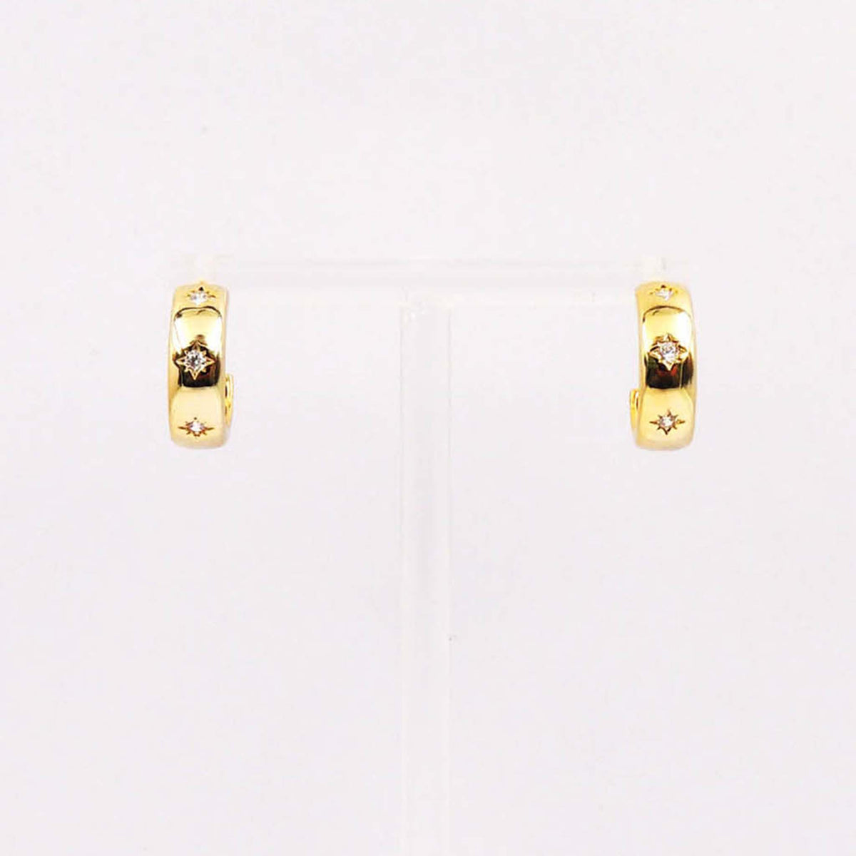 Gold huggie hoop earrings with starburst engravings and crystal accents.