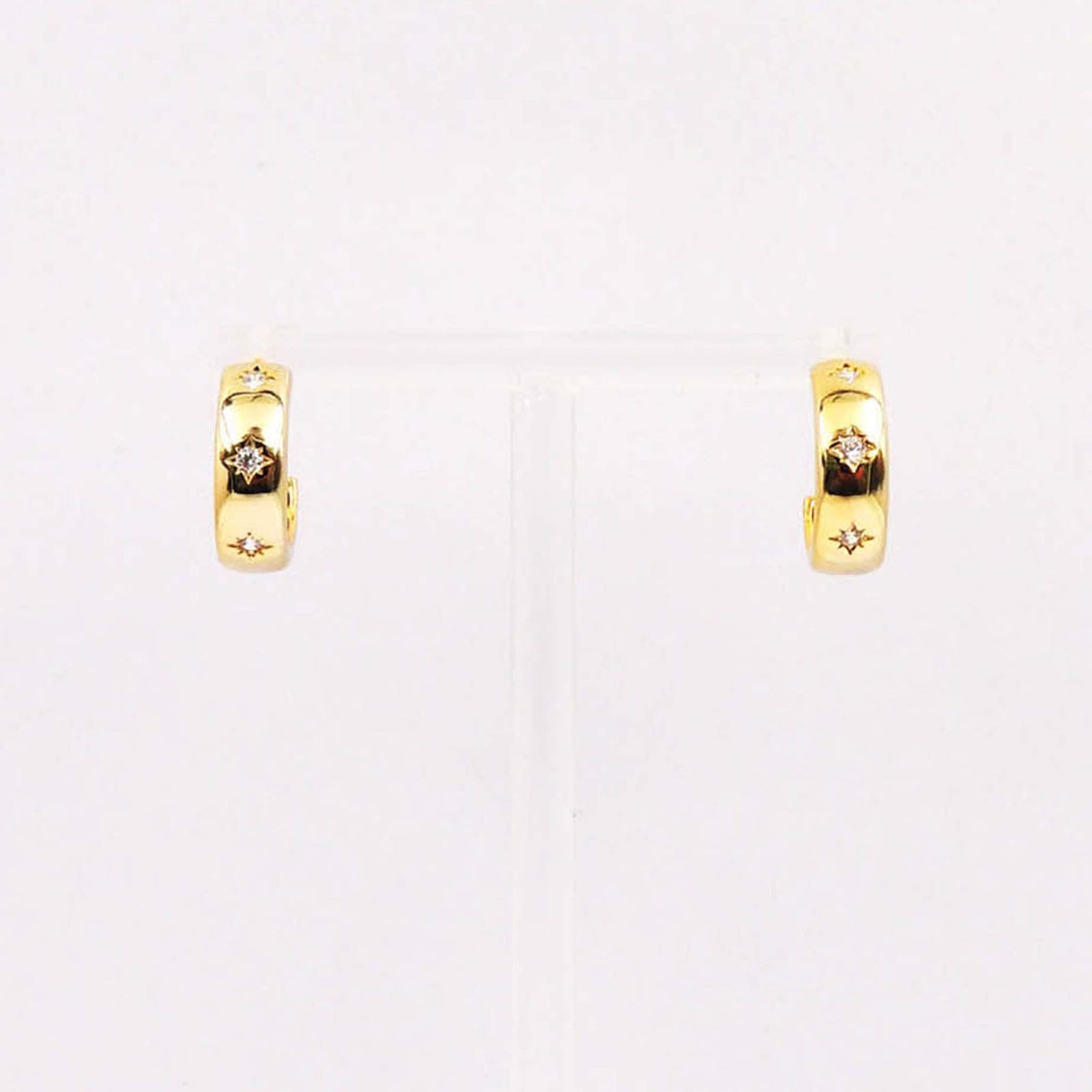 Gold huggie hoop earrings with starburst engravings and crystal accents.
