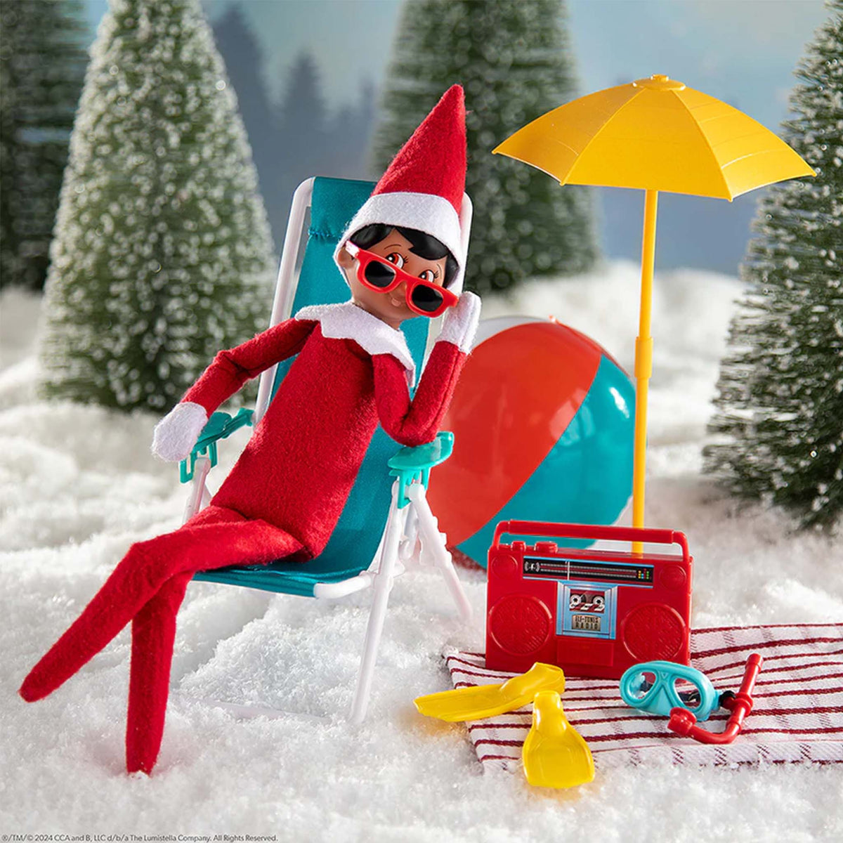 Elf on the Shelf in a red outfit with sunglasses, sitting in a beach chair in the snow.