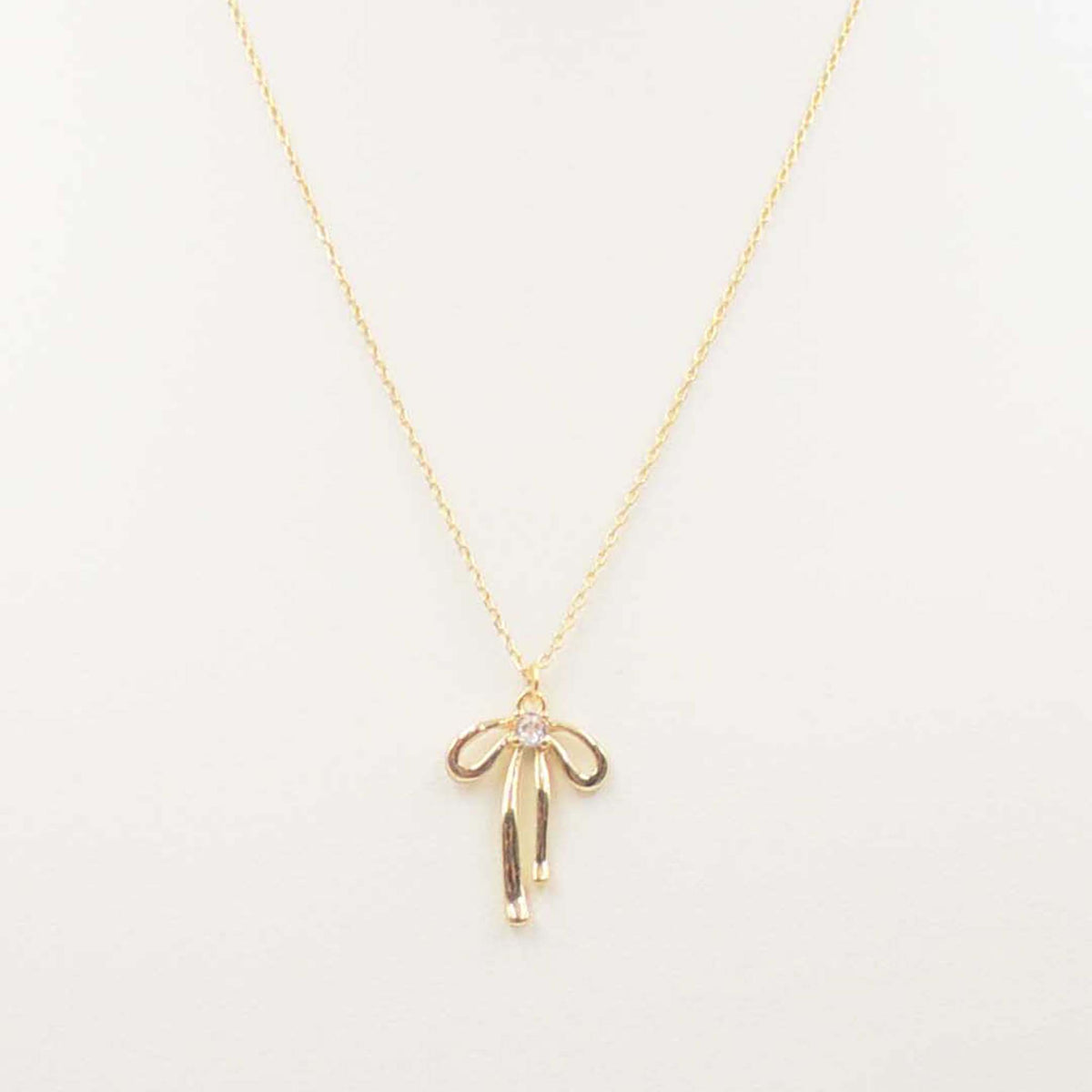 Gold chain necklace with open bow pendant and central crystal accent.