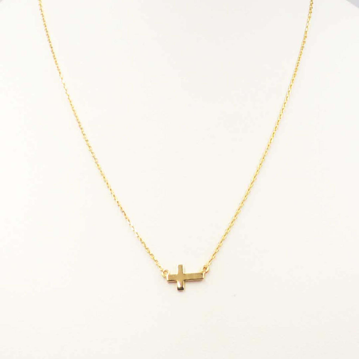 Gold necklace featuring a small horizontal cross pendant centered on a delicate gold chain.
