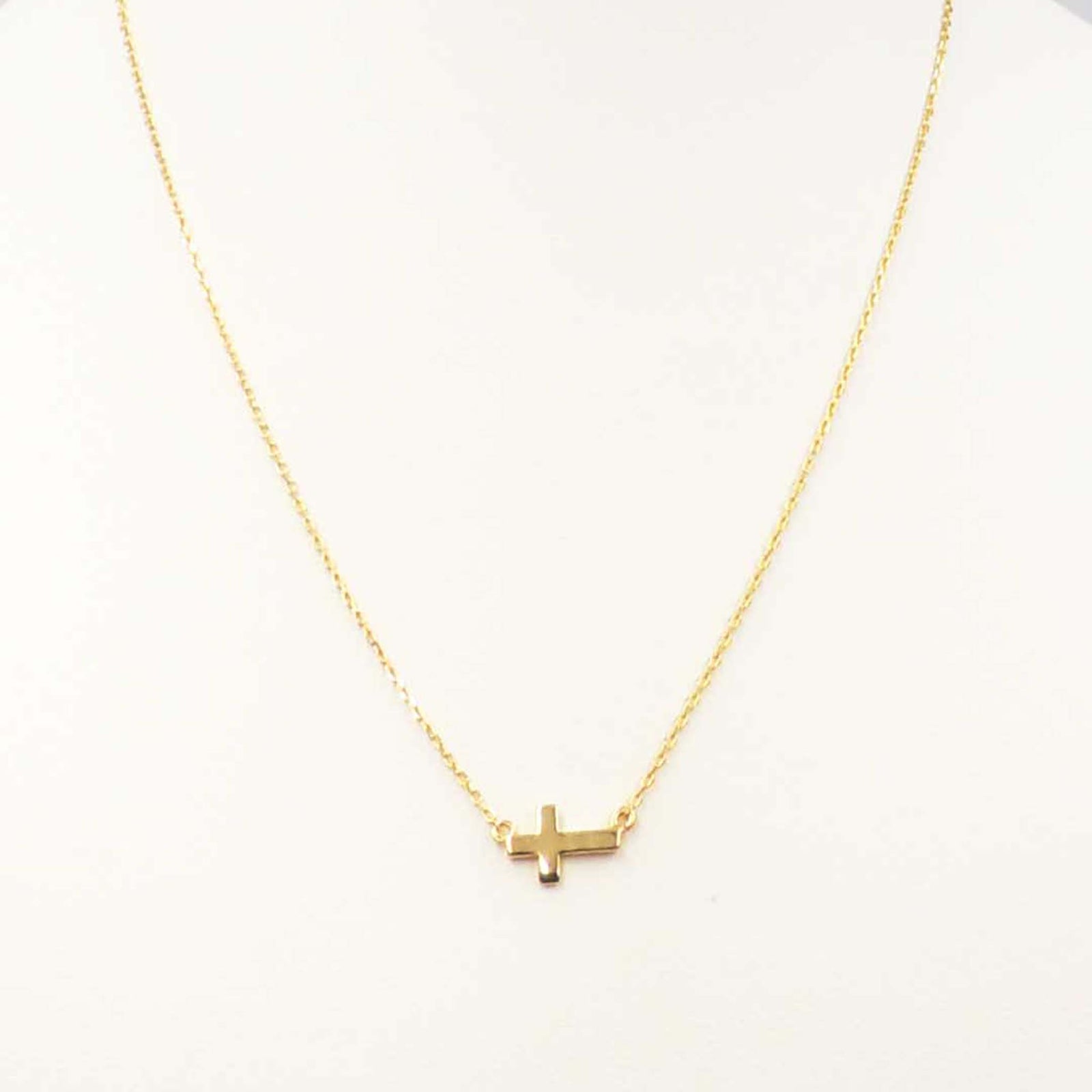 Gold necklace featuring a small horizontal cross pendant centered on a delicate gold chain.