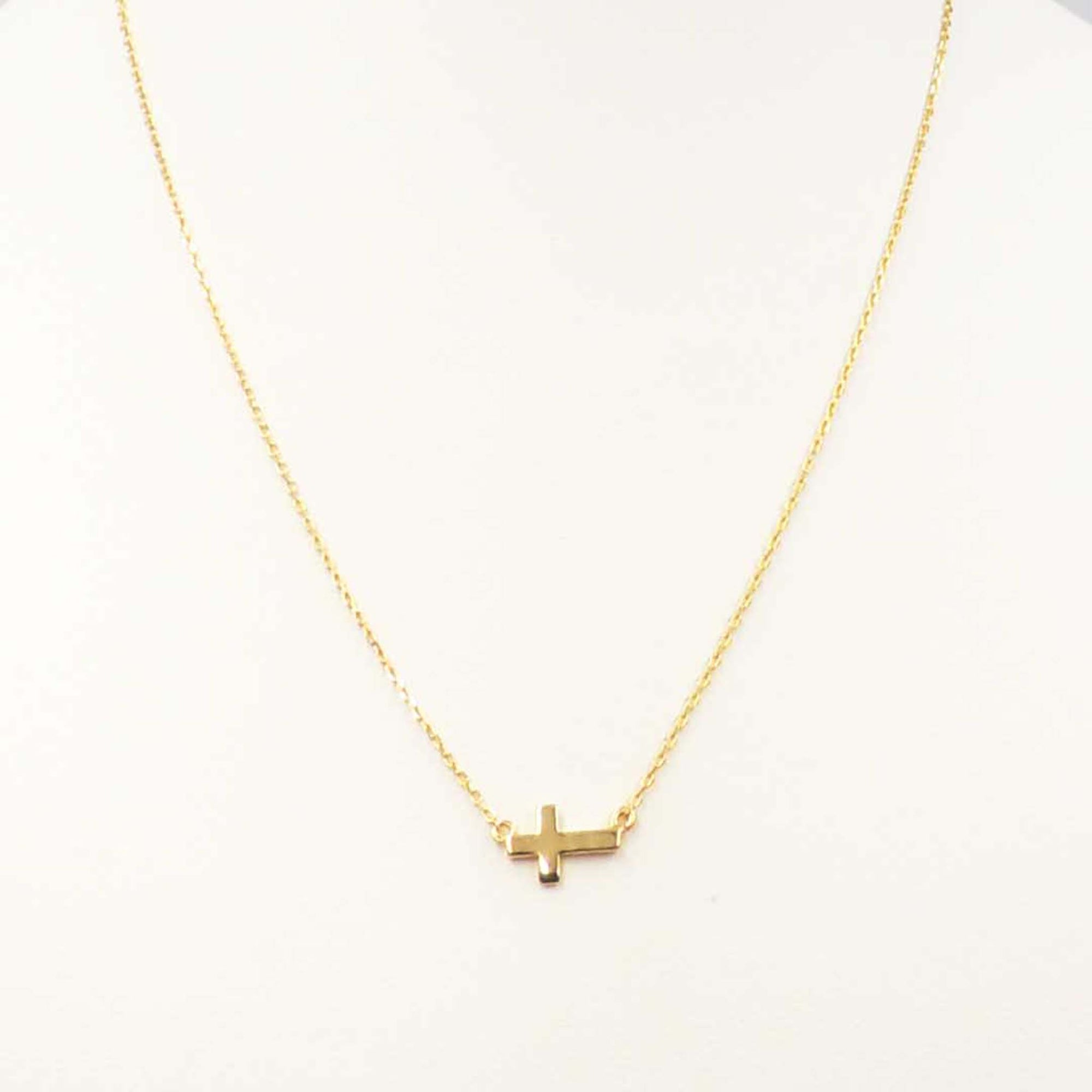 Gold necklace featuring a small horizontal cross pendant centered on a delicate gold chain.