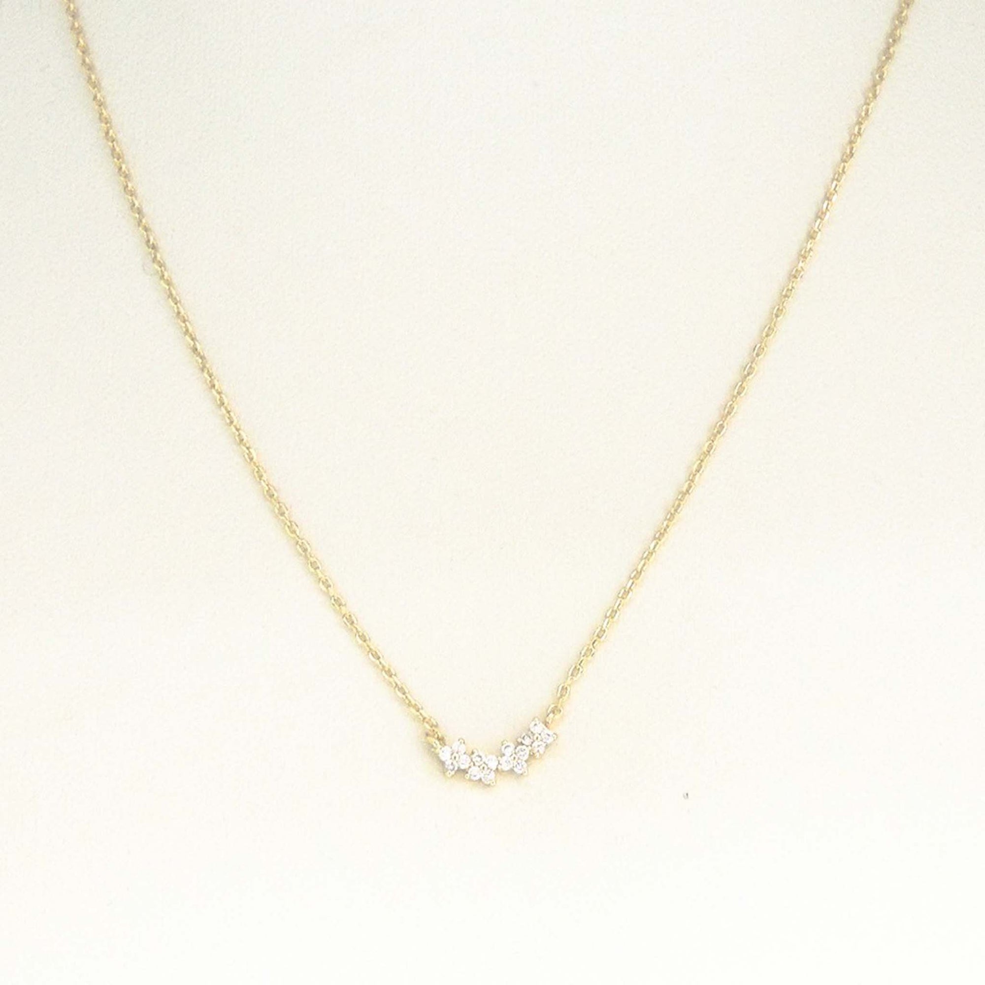 Gold dainty chain necklace with small crystal cluster pendant displayed on a white background.