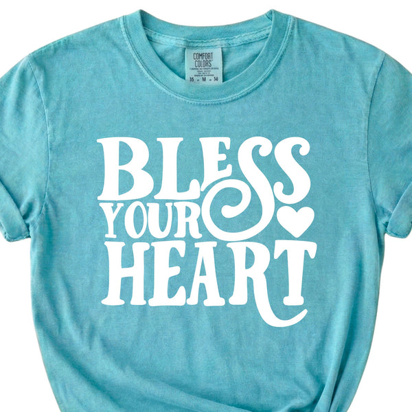 Close-up of chalky mint t-shirt featuring bold white “Bless Your Heart” lettering with decorative script and heart graphic.