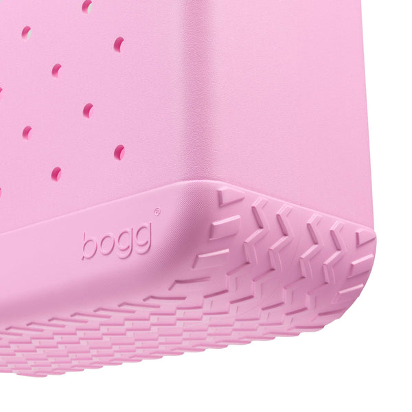 Close-up of the bottom of a pink bogg bag shown on a white background.