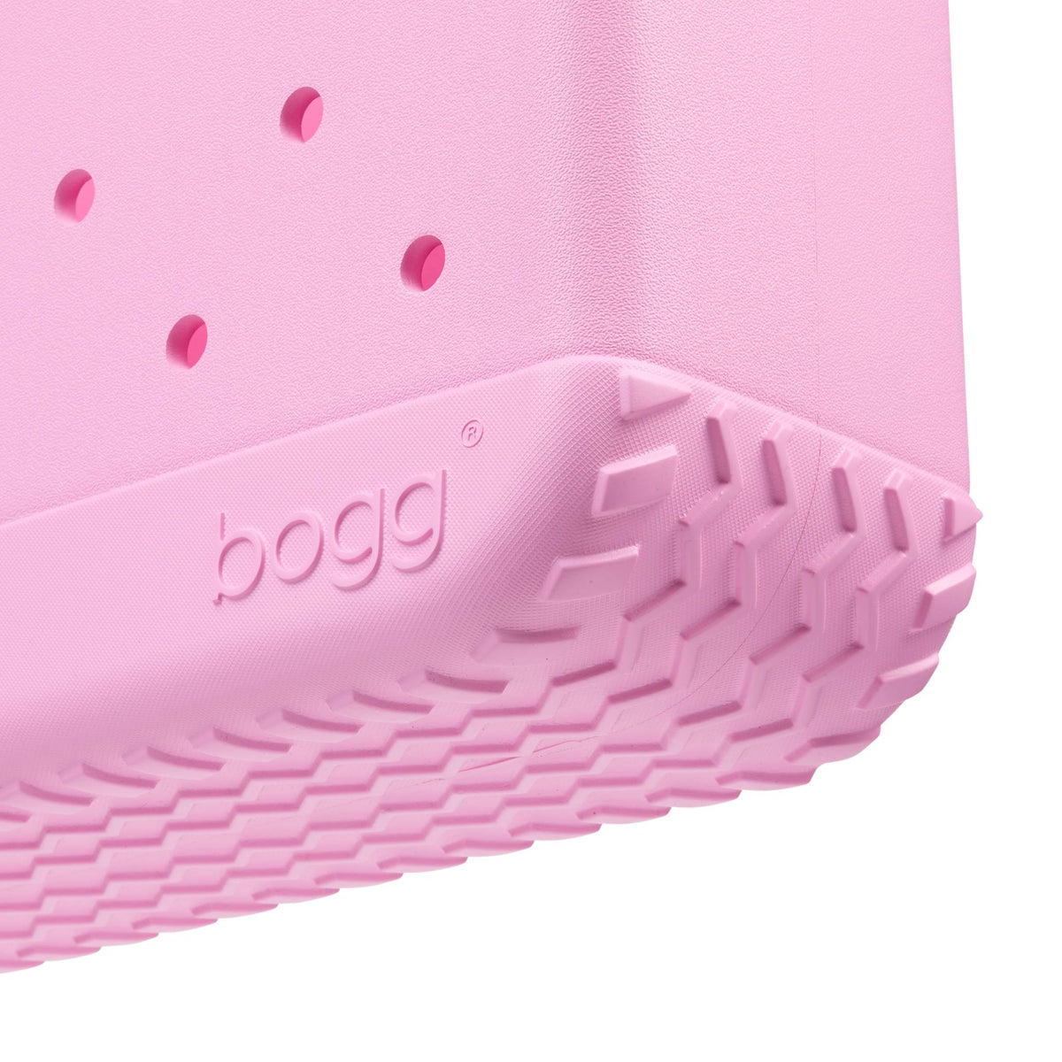 Close-up of the bottom of a pink bogg bag with visible branding on a white background