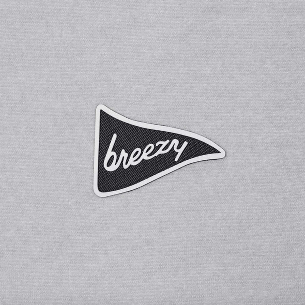 Close-up of Breezy black pennant logo with white script lettering on light grey hoodie fabric.