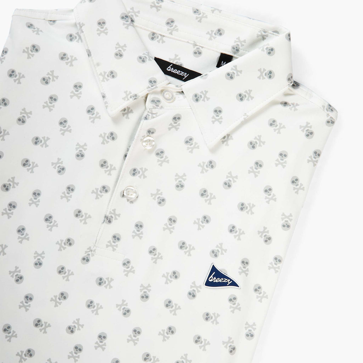 Breezy white performance polo shirt with subtle gray skull and crossbones pattern, three-button placket, and navy pennant logo patch on chest.