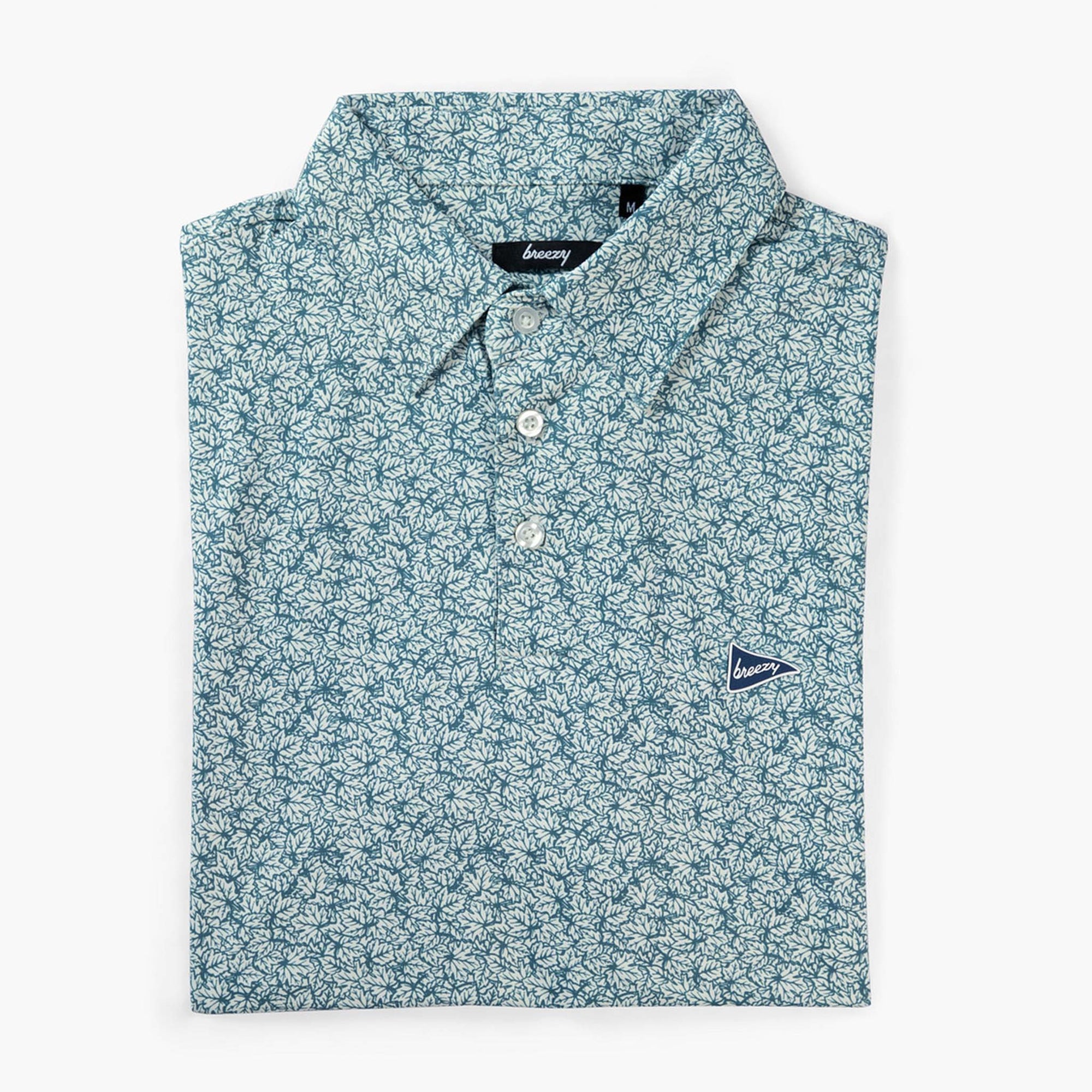 Breezy men’s performance polo in white and green leaf print shown neatly folded with button placket and logo on chest.