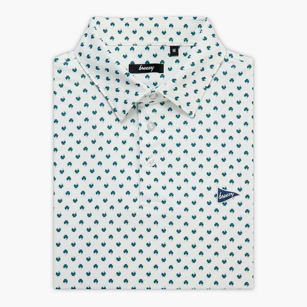 Folded white polo shirt with green clover pattern and 'Breezy' branding shown on a white background