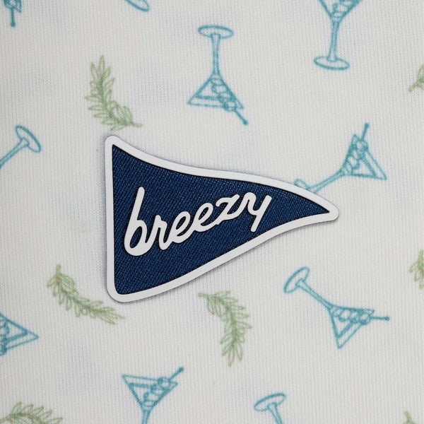 Patch with 'breezy' text on a fabric background with cocktail patterns