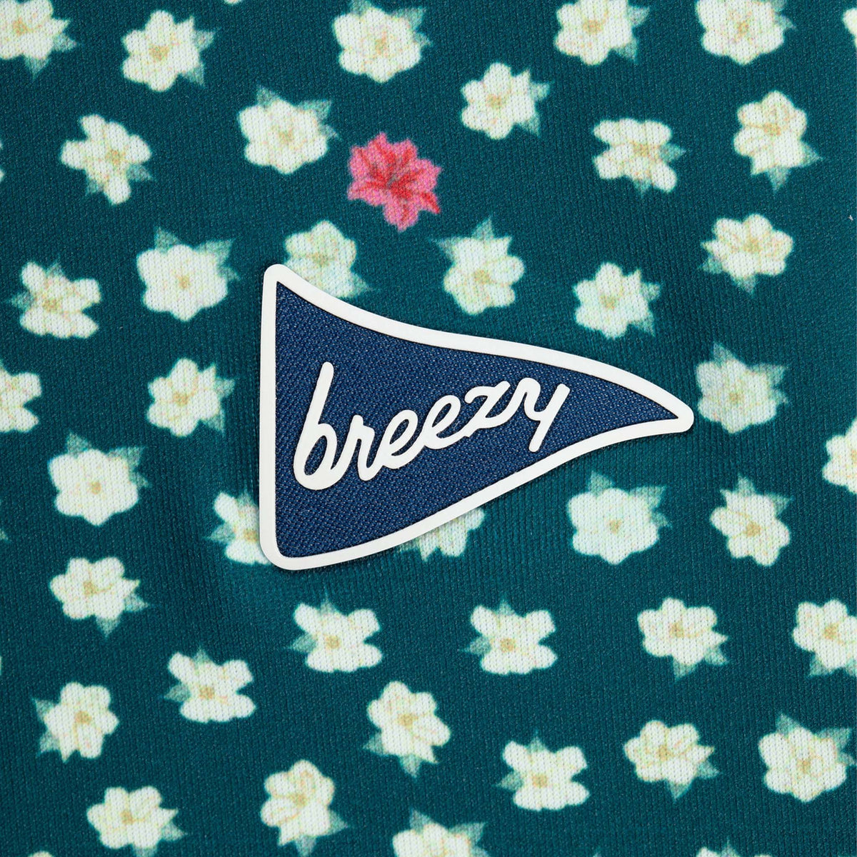 Floral patterned fabric with a 'breezy' patch on a green background