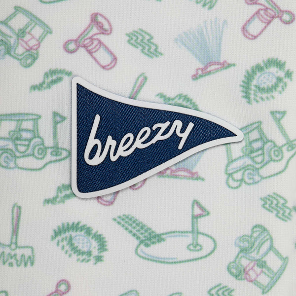 Patch with 'breezy' text on a fabric background with golf-themed patterns
