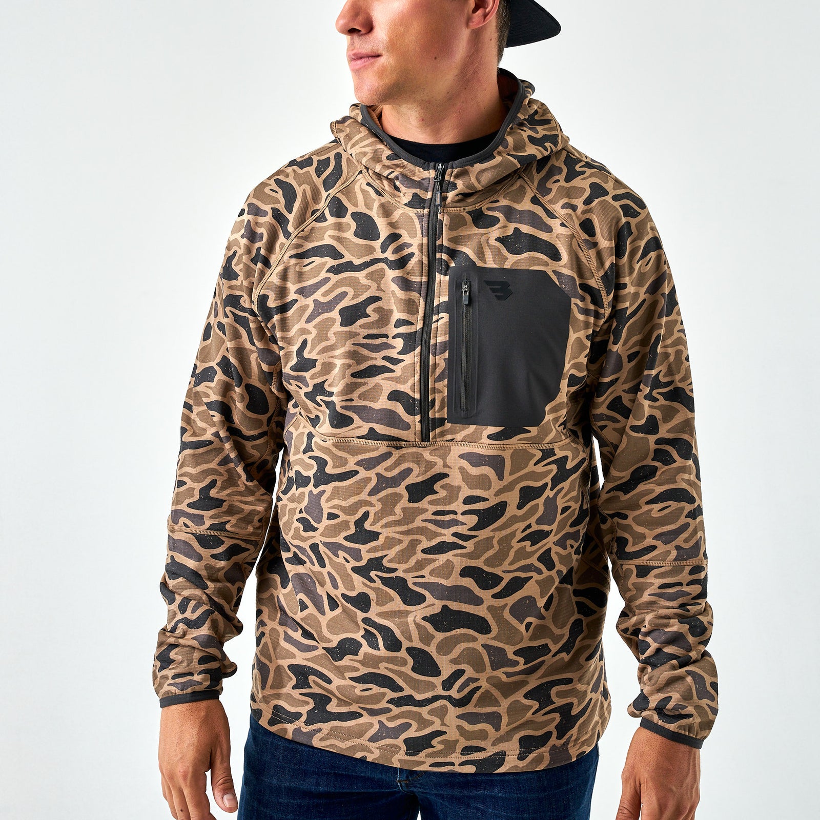 Men’s brown and black camo quarter-zip hoodie with solid black chest pocket, worn by model standing with hands at sides.