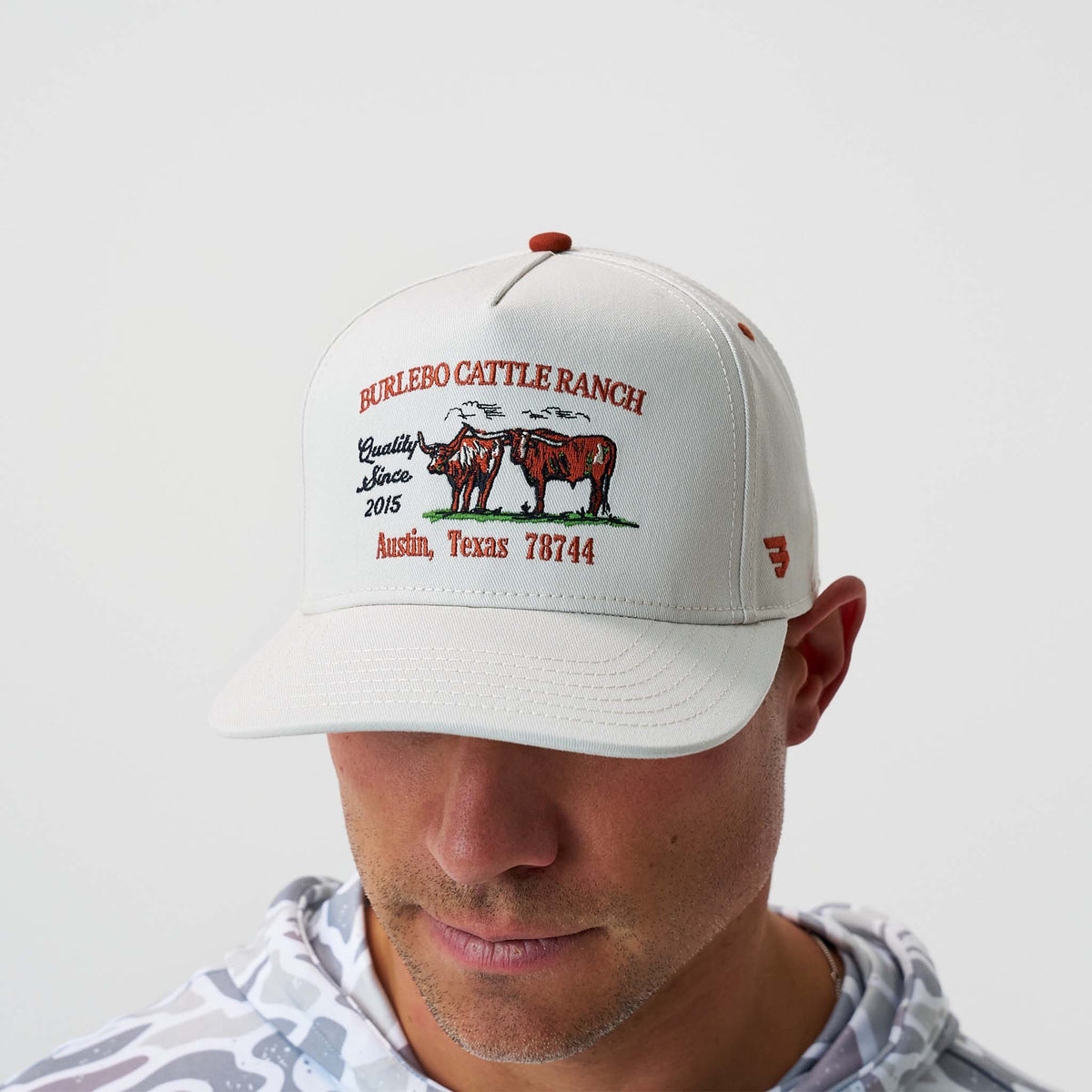 Person wearing a white cap with 'Burlebo Cattle Ranch' branding on a light gray background