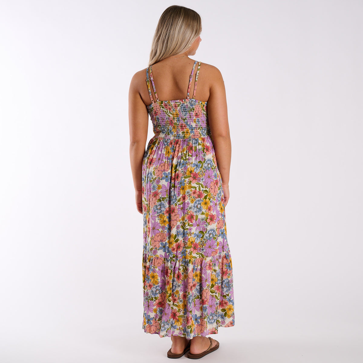 Woman wearing a colorful floral and lace inset sleeveless maxi dress on a white background