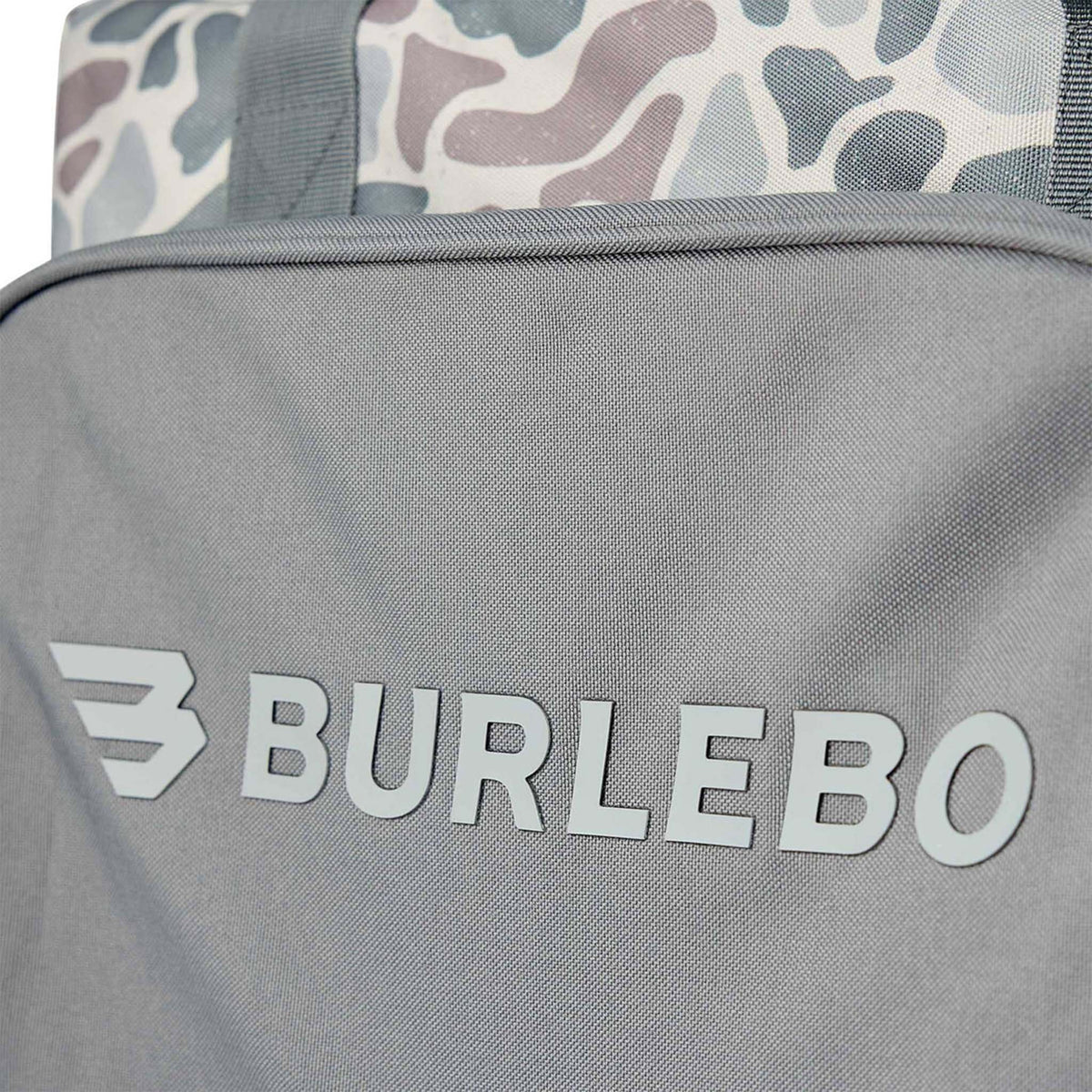 Close-up of BURLEBO logo on gray front pocket of camo cooler bag with durable textured fabric.