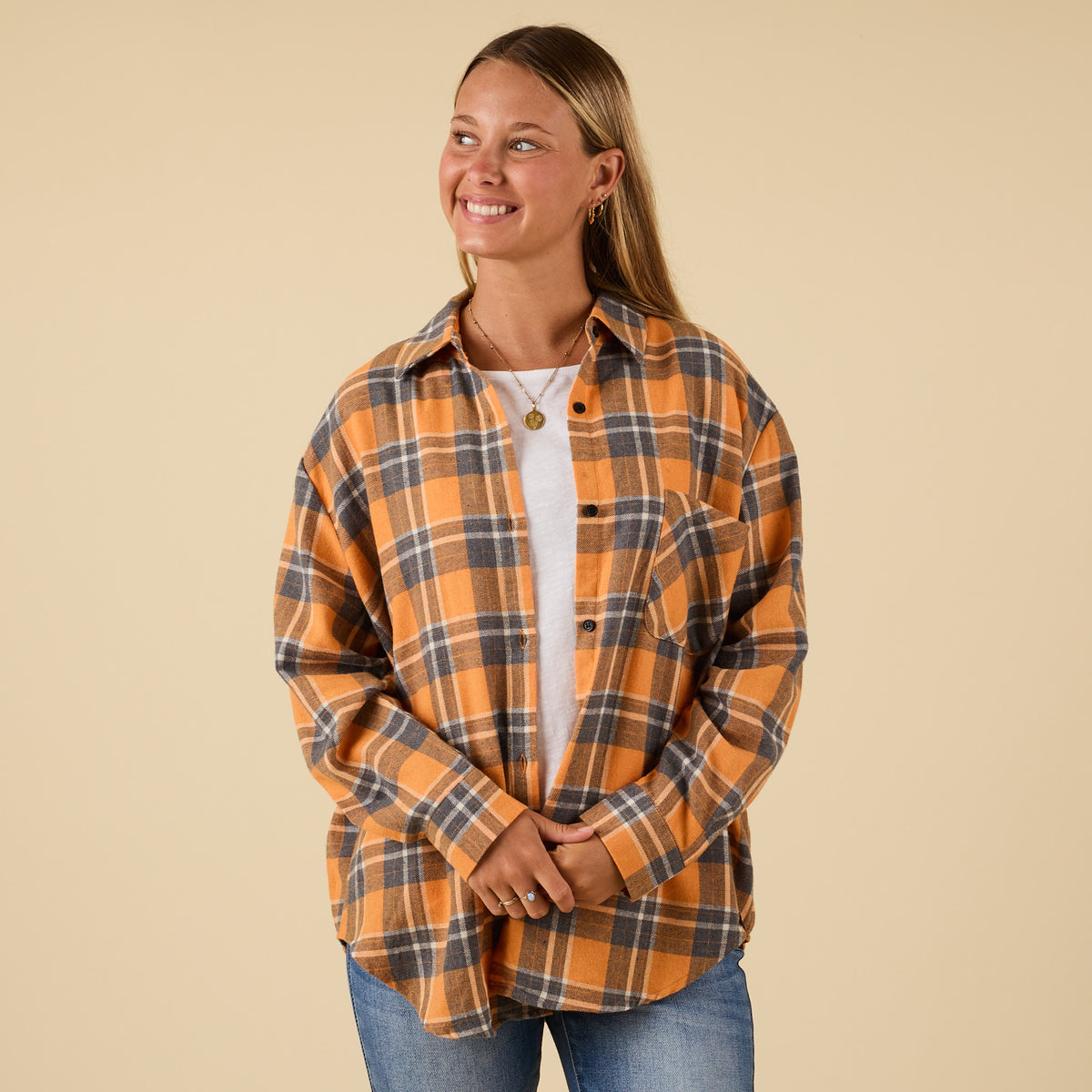 Woman wearing an orange and black plaid shirt against a beige background