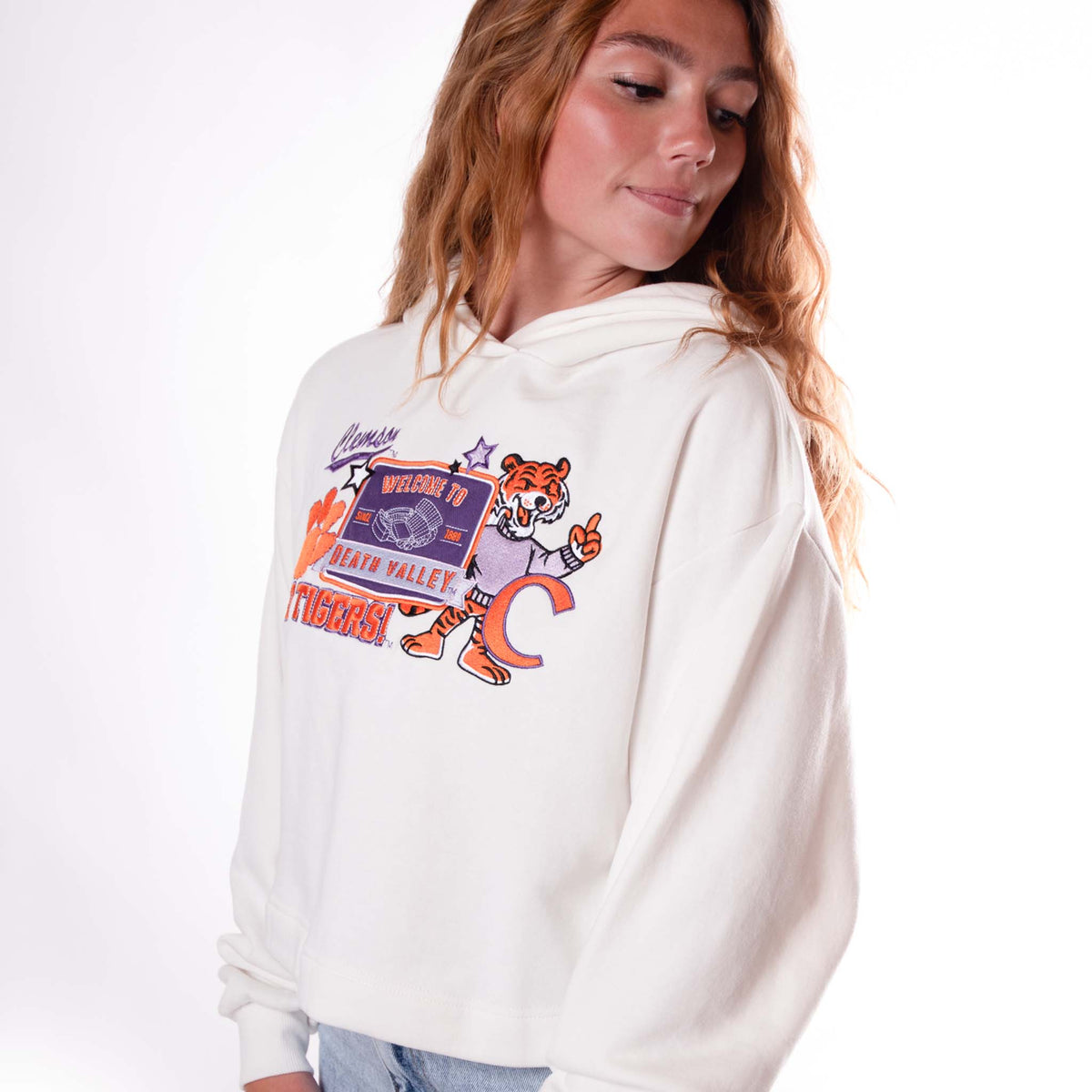 Side view of white cropped Clemson hoodie featuring layered mascot patch graphic.