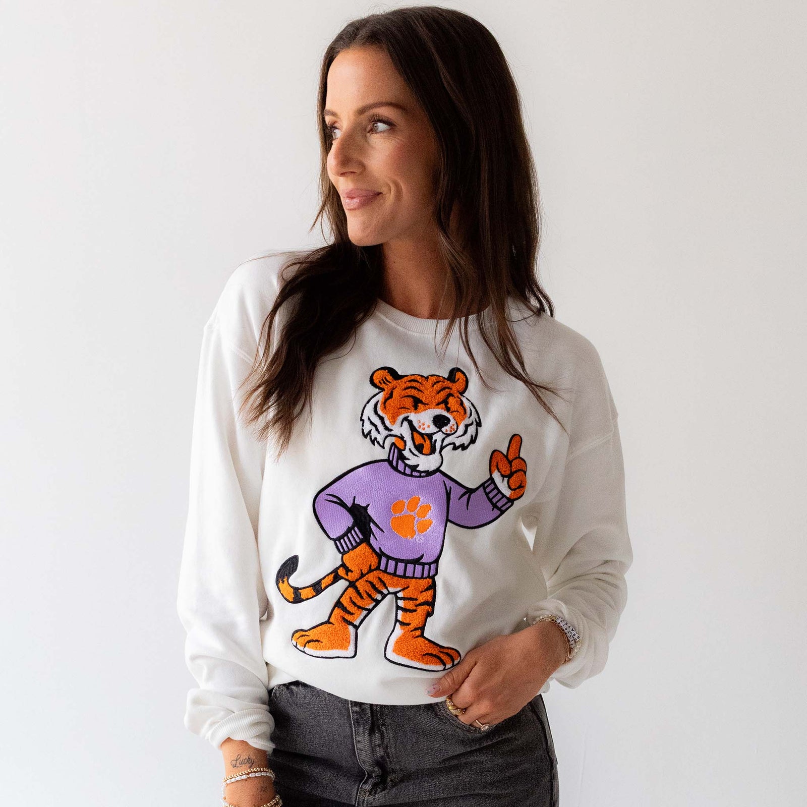 Front view of white crewneck sweatshirt featuring chenille tiger mascot patch.