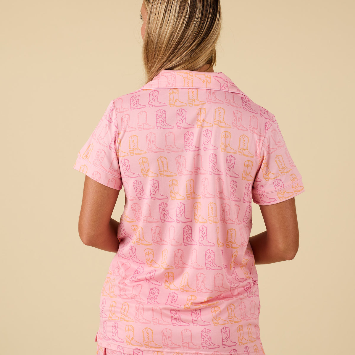 Back view of pink pajama top with short sleeves and colorful cowboy boot print.