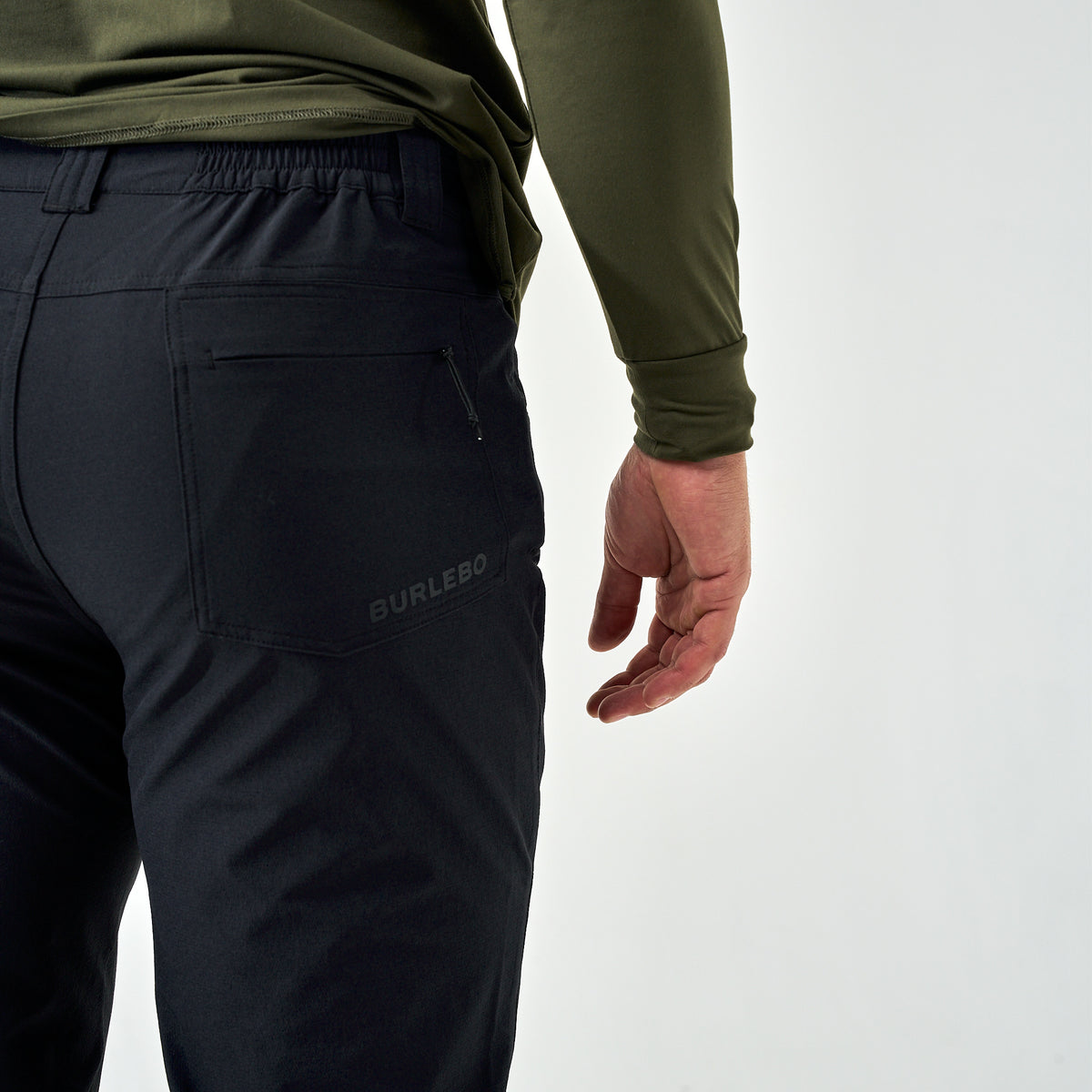 Back view of Burlebo Challenger Pants in black with logo above pocket, styled with an olive long sleeve shirt.