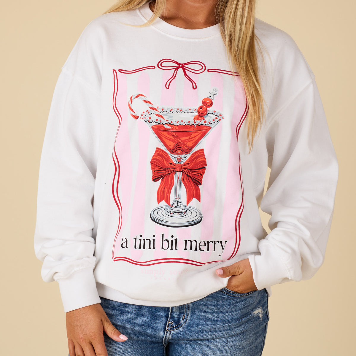 Close-up of Simply Southern white sweatshirt featuring martini glass with candy cane, cranberries, sugar rim, red bow, and “a tini bit merry” text.