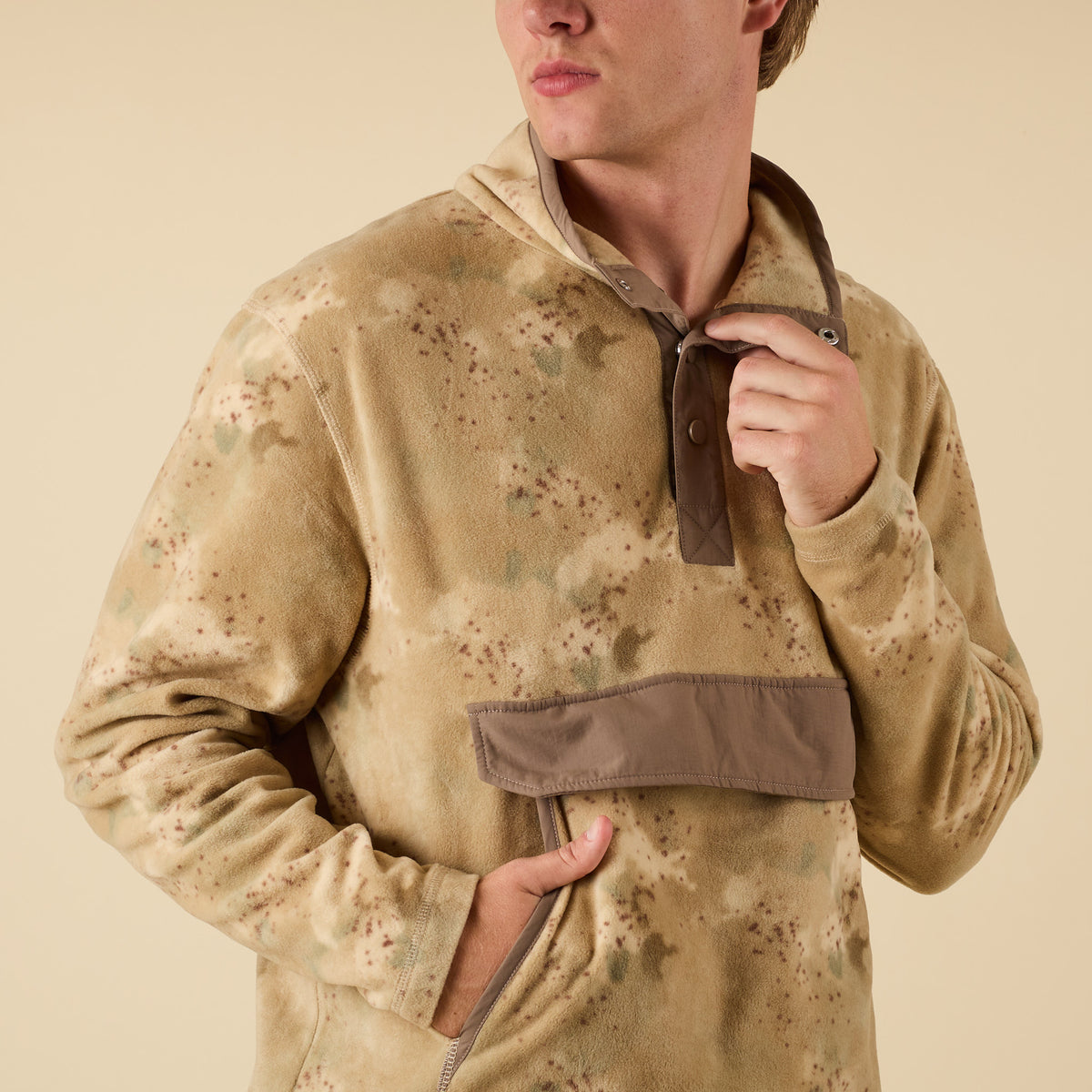 Person wearing a camouflage pullover with a neutral background