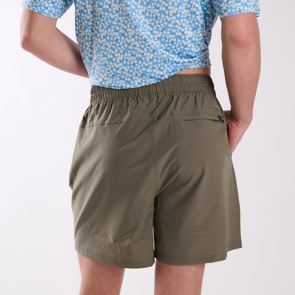 Person wearing olive green shorts and a blue patterned shirt on a white background