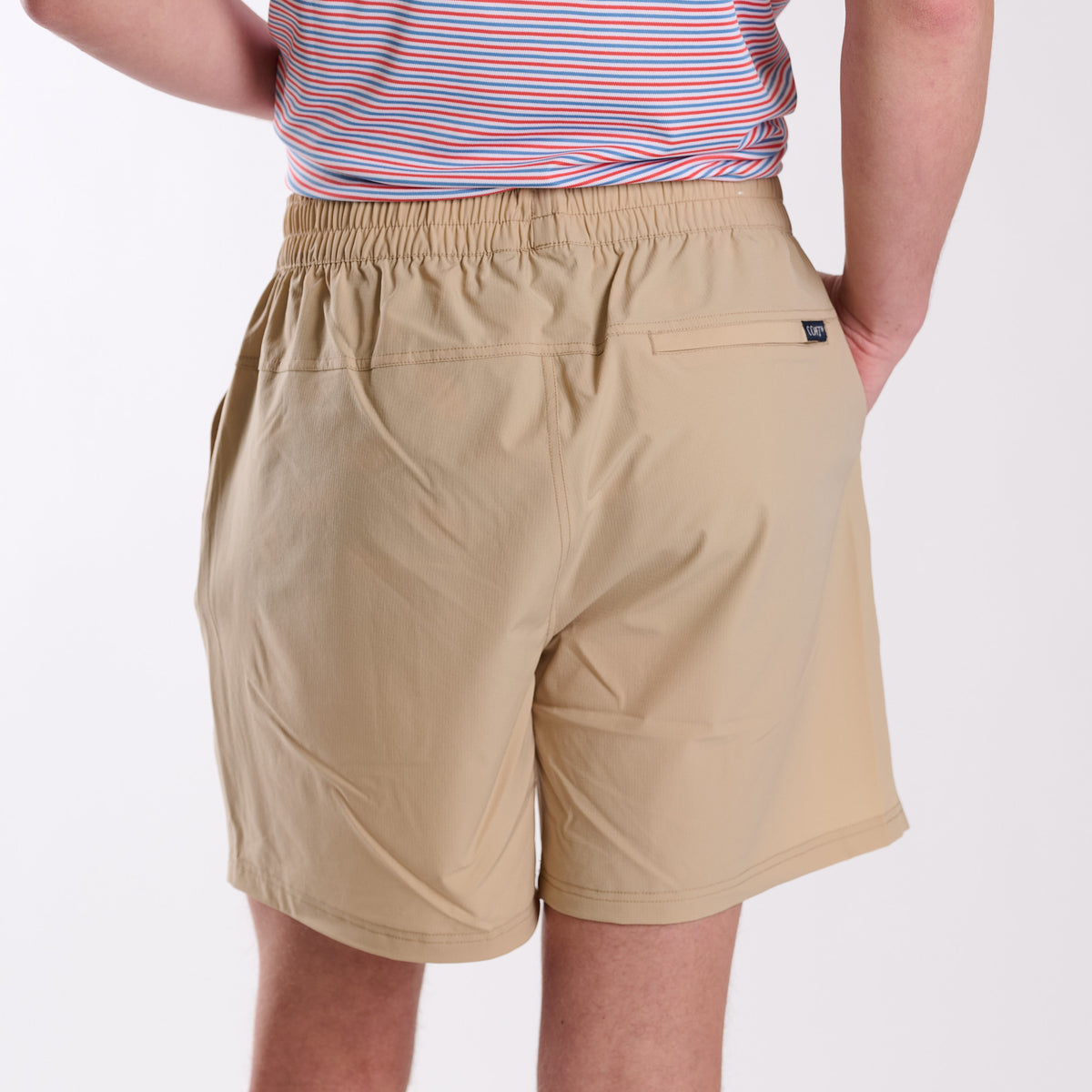 Beige shorts worn by a person on a white background