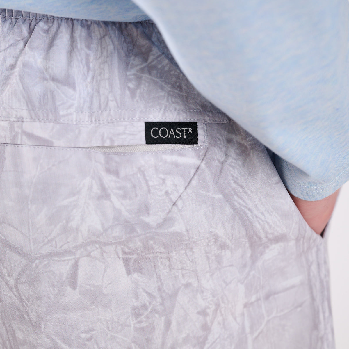 Close-up of camo patterned shorts with a 'COAST' label on a light blue garment.