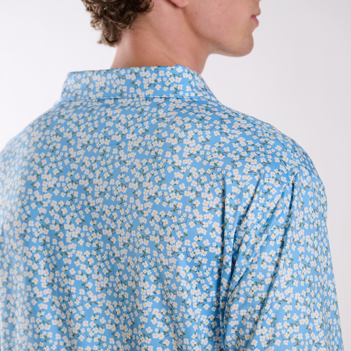 Man wearing a blue floral patterned shirt on a white background