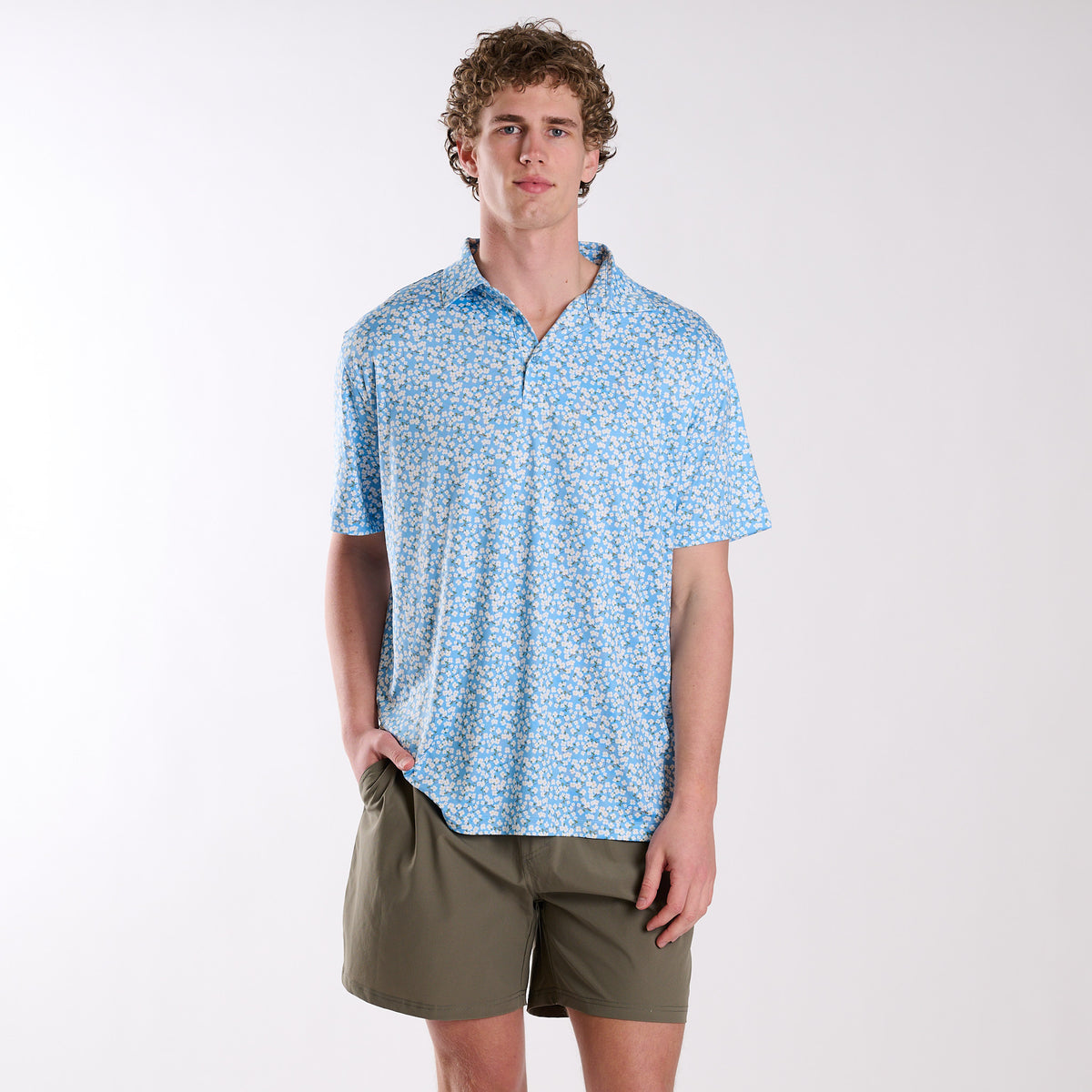 Man wearing a blue patterned shirt and green shorts on a white background
