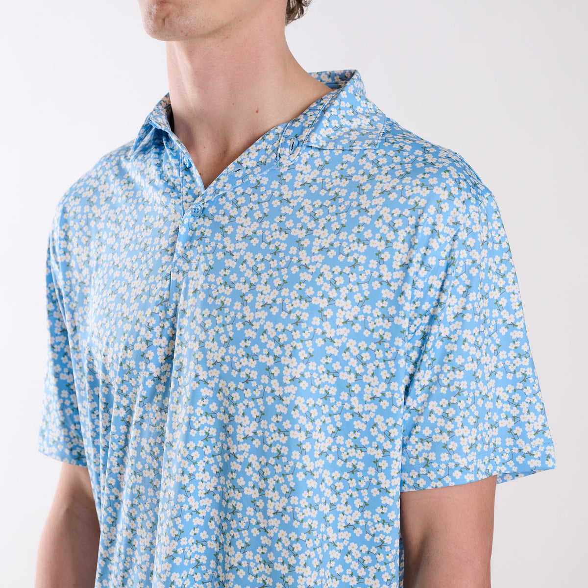 Person wearing a blue floral patterned shirt on a white background