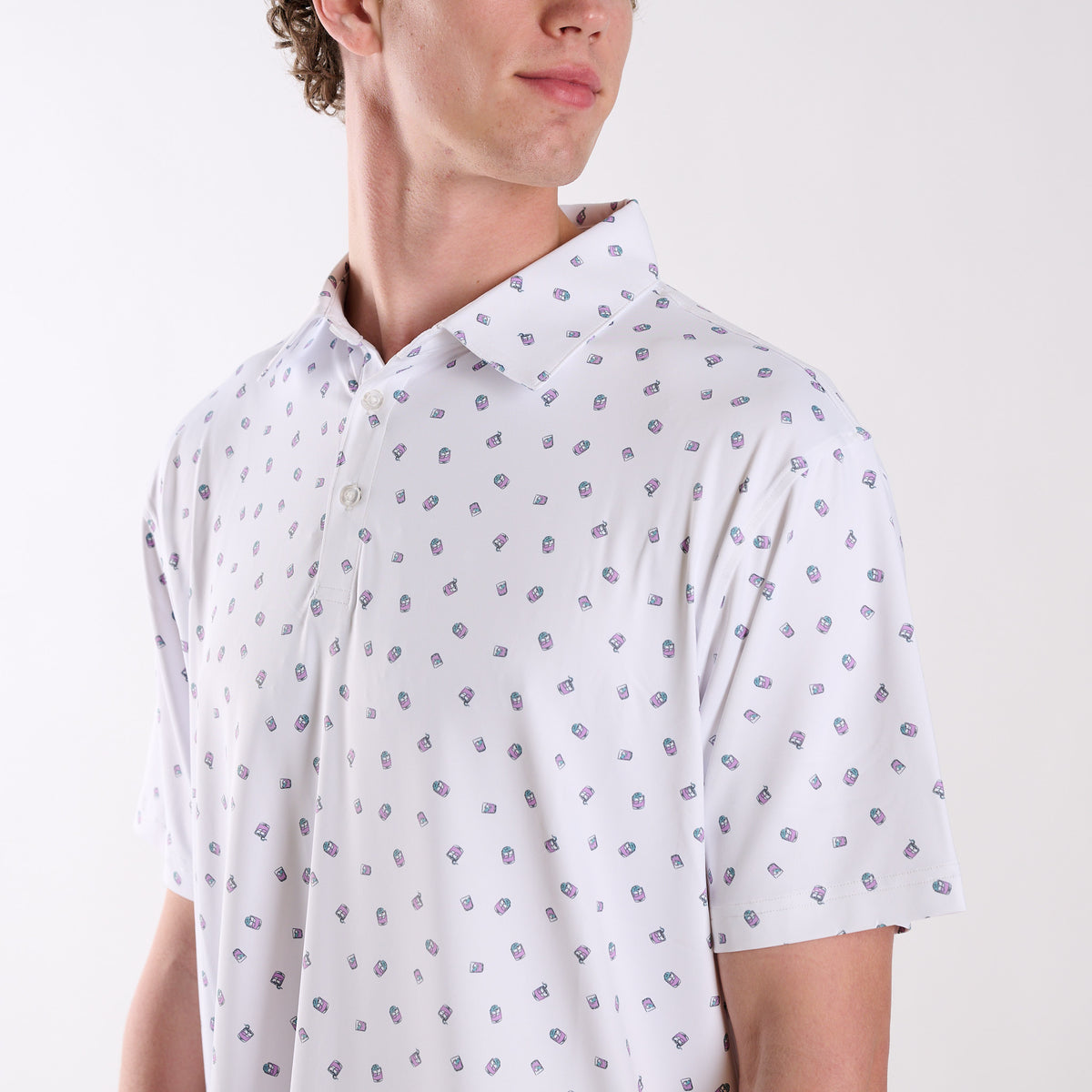 Close-up of COAST Transfusion Icon Printed Polo in white featuring small pink and teal transfusion drink icons and a classic collar with button placket.