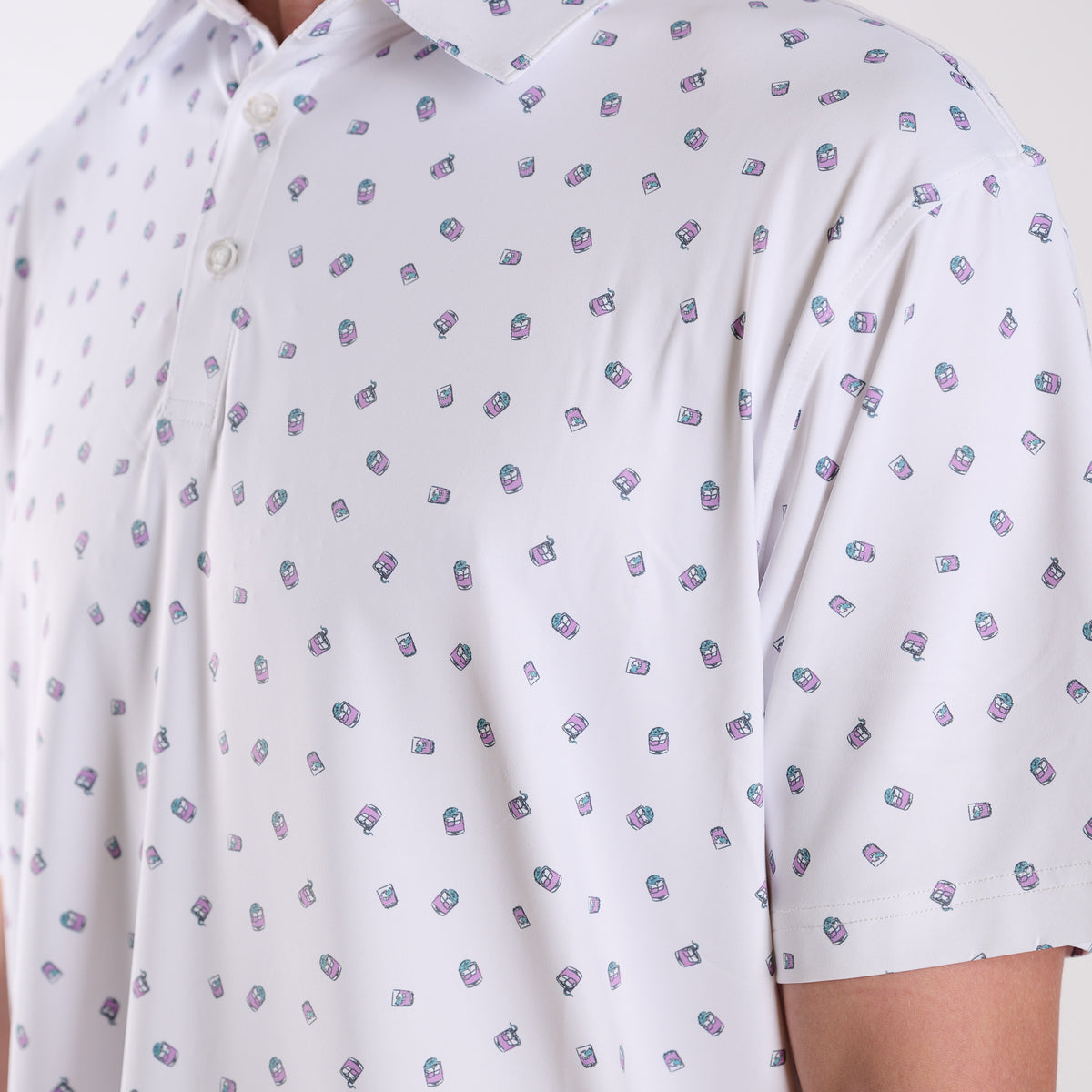 Close-up of COAST Transfusion Icon Printed Polo in white featuring small pink and teal transfusion drink icons and a classic collar with button placket.