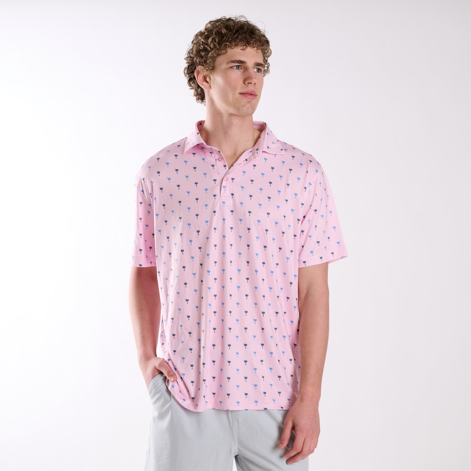 COAST South Carolina Palm Tree Printed Polo in pink with small blue and navy palmetto tree print, shown on a model in a studio setting.