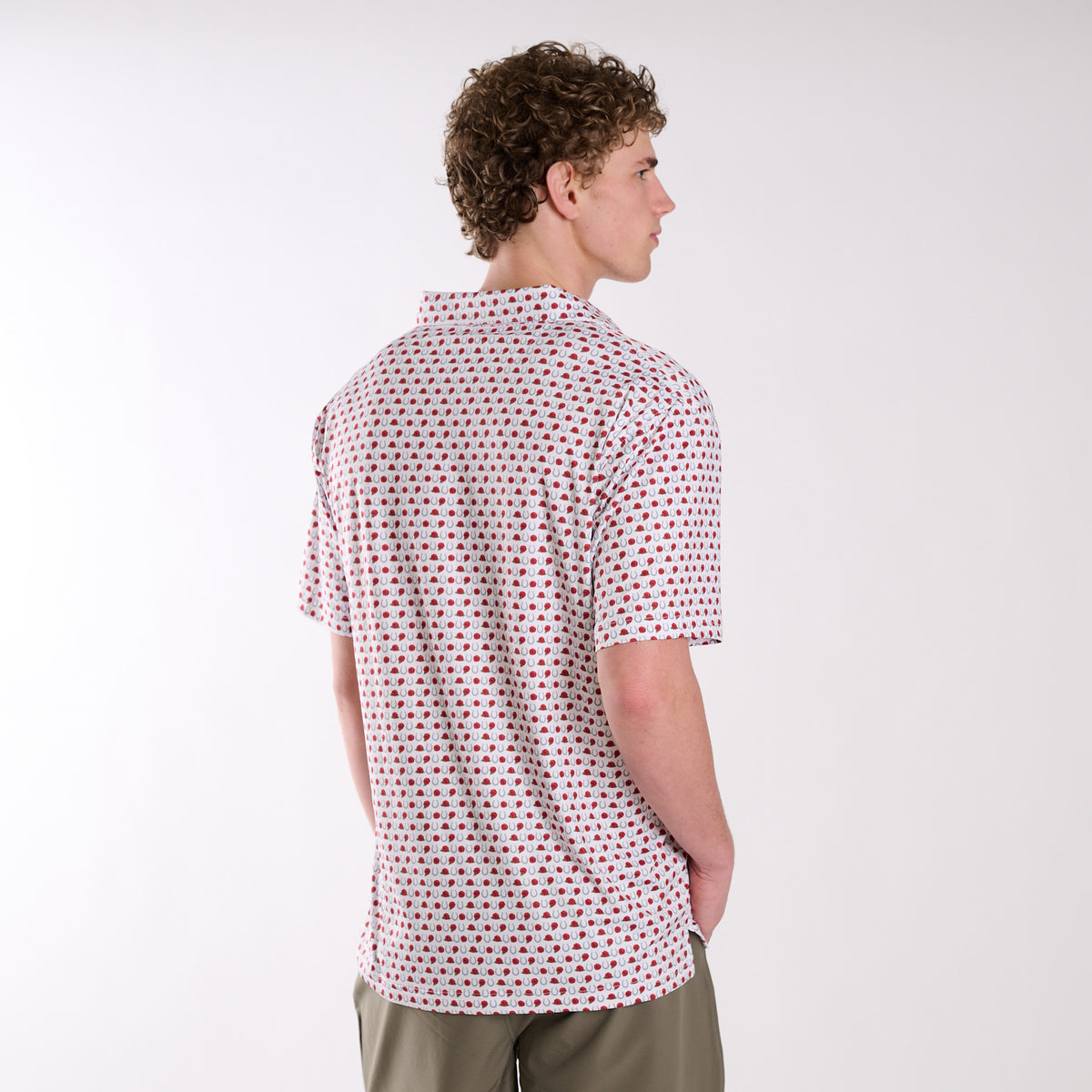Man wearing a patterned horseshoe and rose polo on a white background