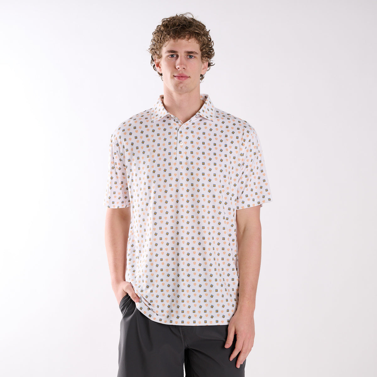 COAST Tennessee Whiskey Tri Star Printed Polo in white with repeating whiskey glass and orange Tennessee tri-star icons, shown on a model in a studio setting.