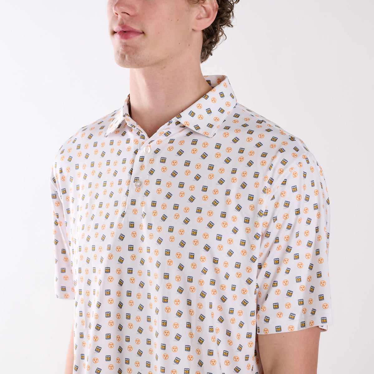 Close-up of COAST Tennessee Whiskey Tri Star Printed Polo in white showing the whiskey glass and orange tri-star pattern with classic collar and button placket.