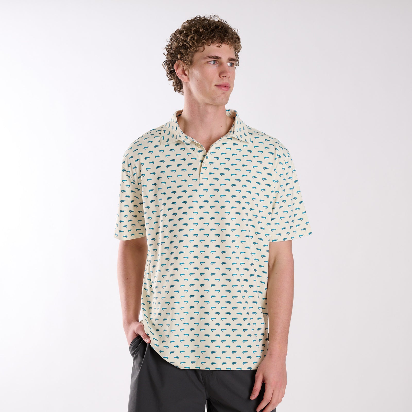 Front view of COAST Florida Gator Printed Polo in light yellow with all-over teal alligator print, worn by a model with dark shorts.