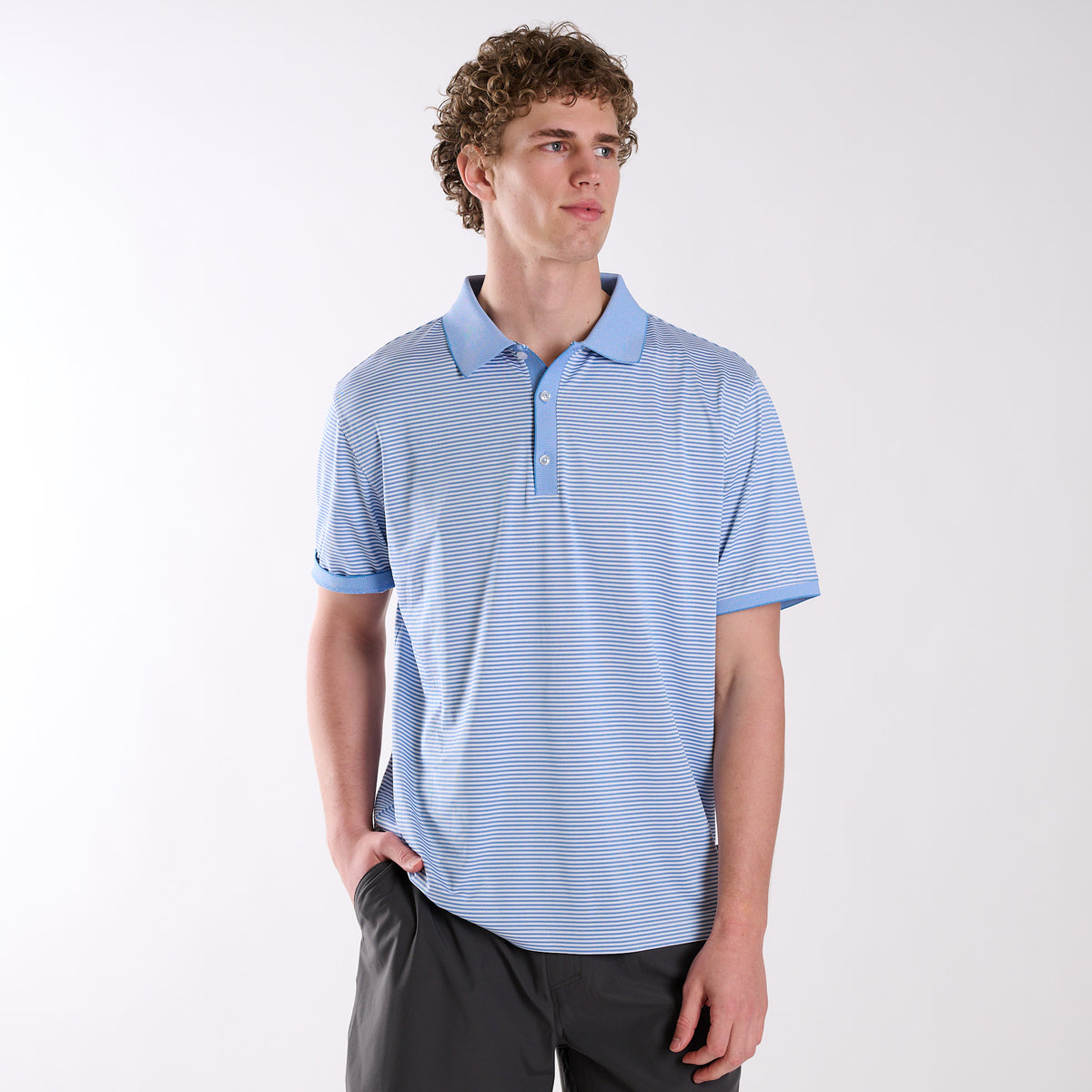 COAST Stripe Performance Polo with micro-stripe pattern, worn by a model with dark shorts against a light studio background.