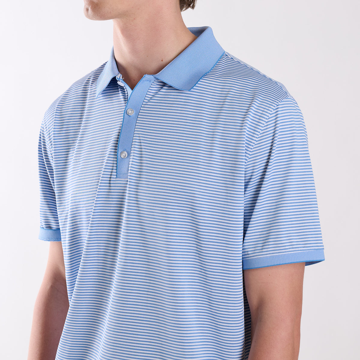 Close-up of COAST Stripe Performance Polo showing the micro-stripe fabric, collar, and three-button placket detail.