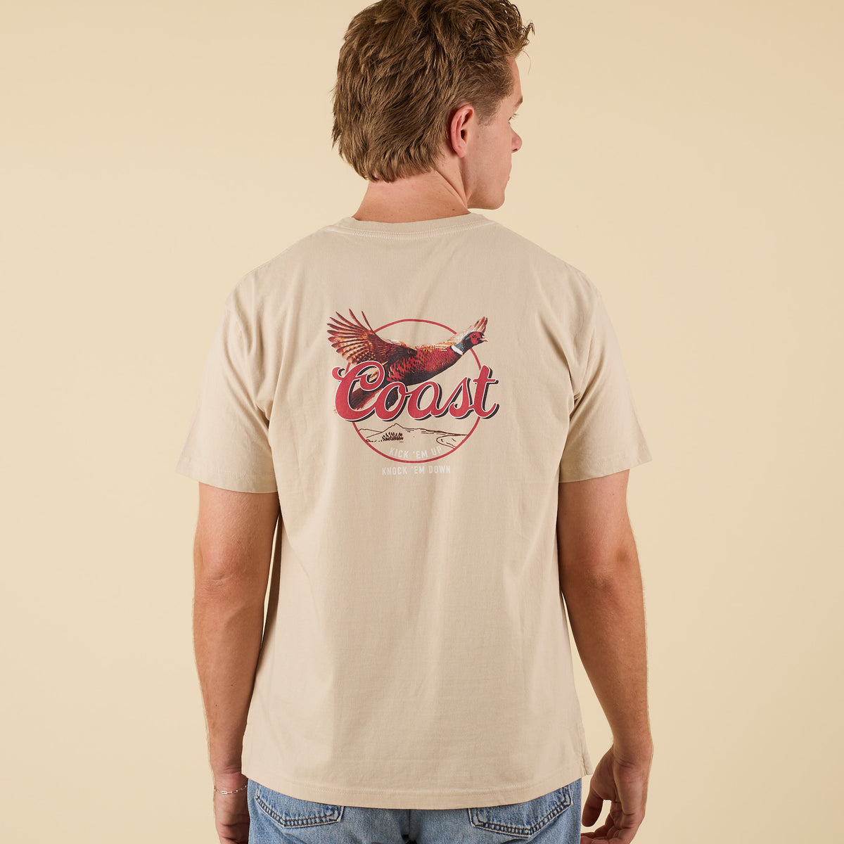 Angled back view of COAST Pheasant beige t-shirt showing bold pheasant graphic design across back.