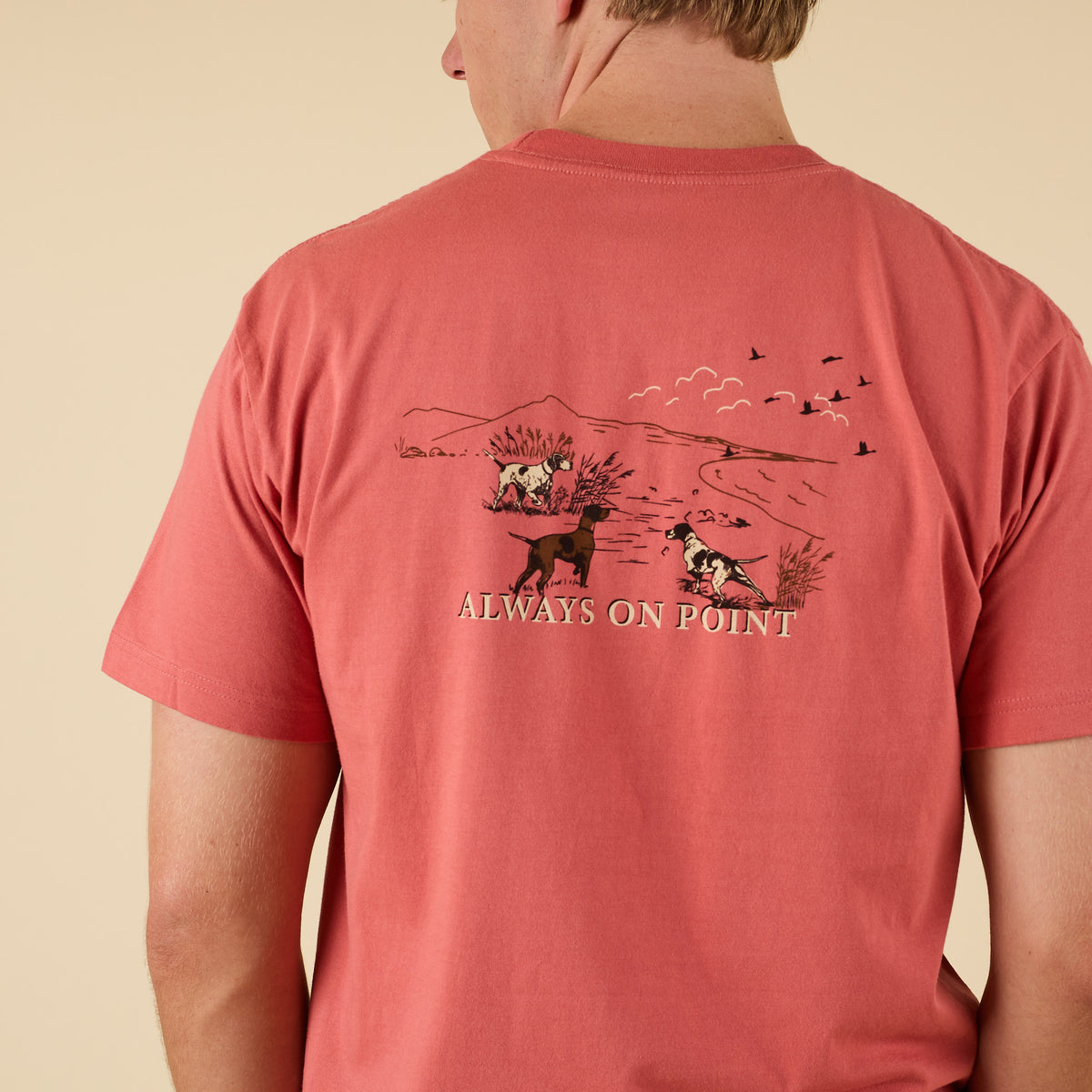 Close-up of back graphic on COAST Always On Point tee featuring hunting dogs and outdoor scenery.